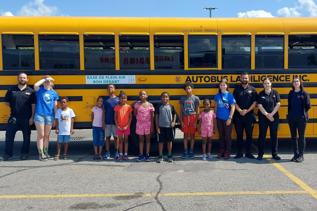 Enfants devant un autobus prêt pour le départ vers la Base de plein air Bon départ